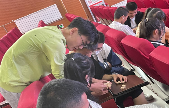 图为实践团成员陈运笑和贵德中学的同学们研究鲁班球